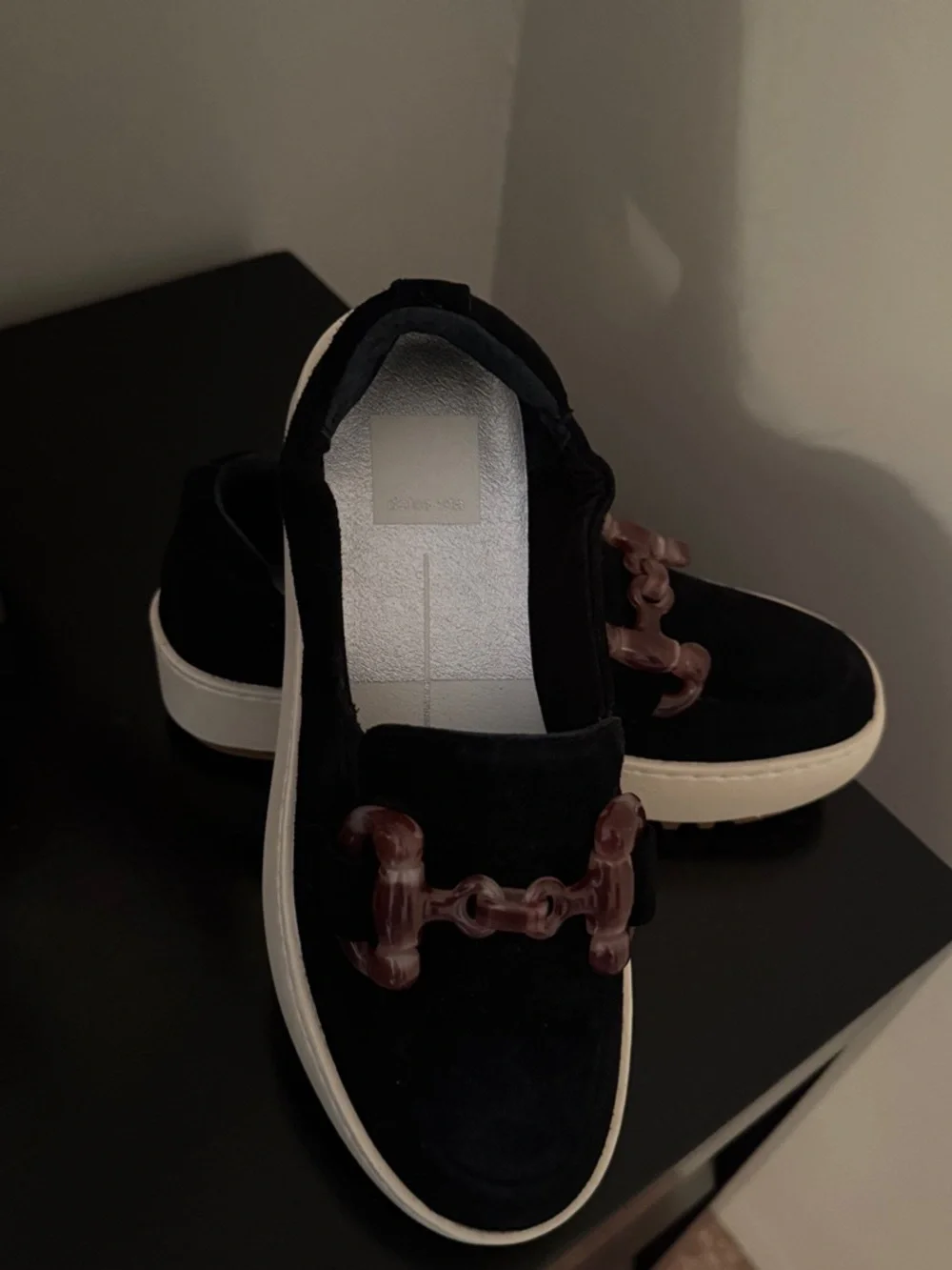 Dolce Vita Black Suede women’s Slip-On Loafers with Brown Accent Chain.